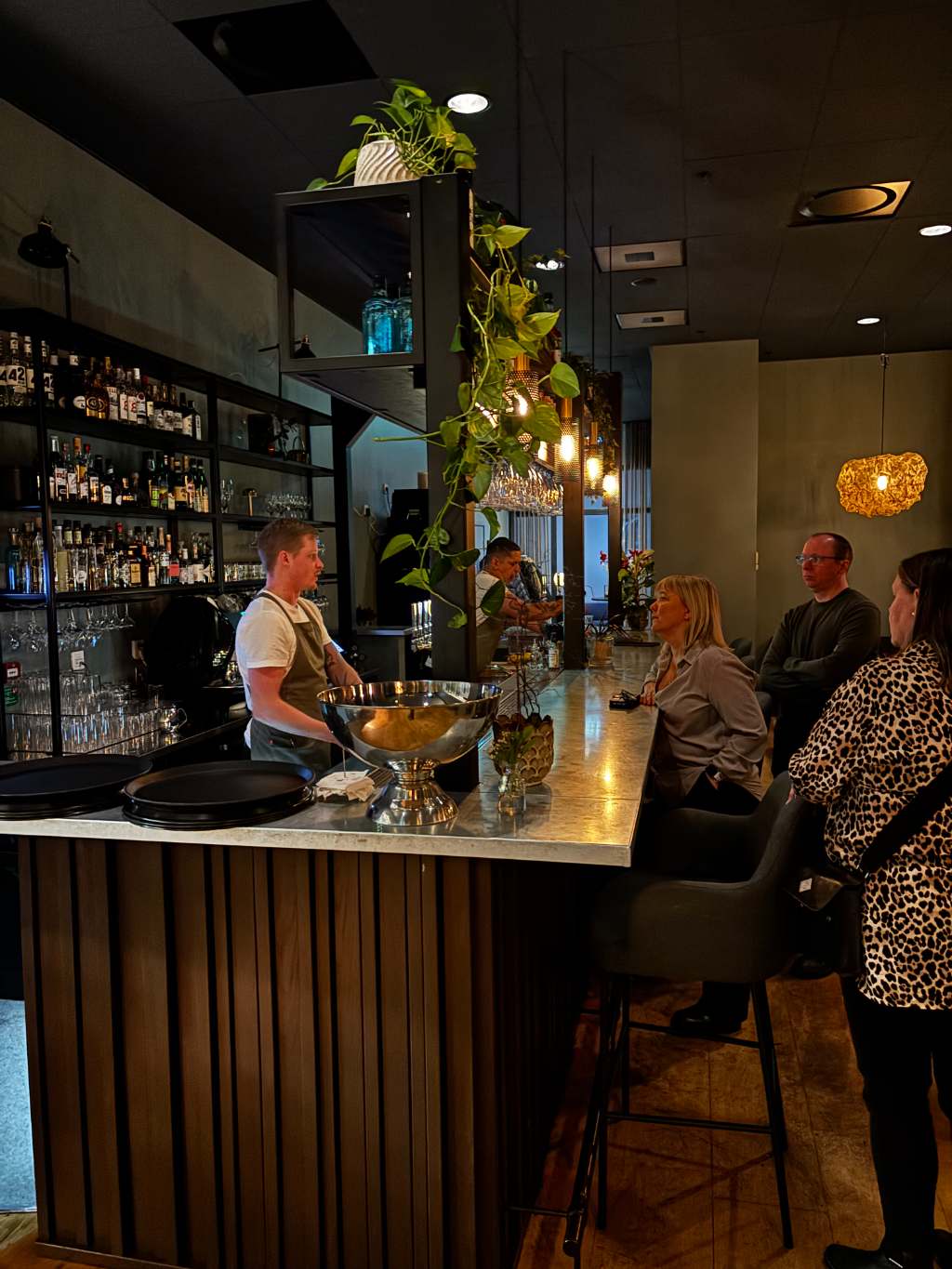 Restauranglokal med personal bakom baren och gäster vid disken